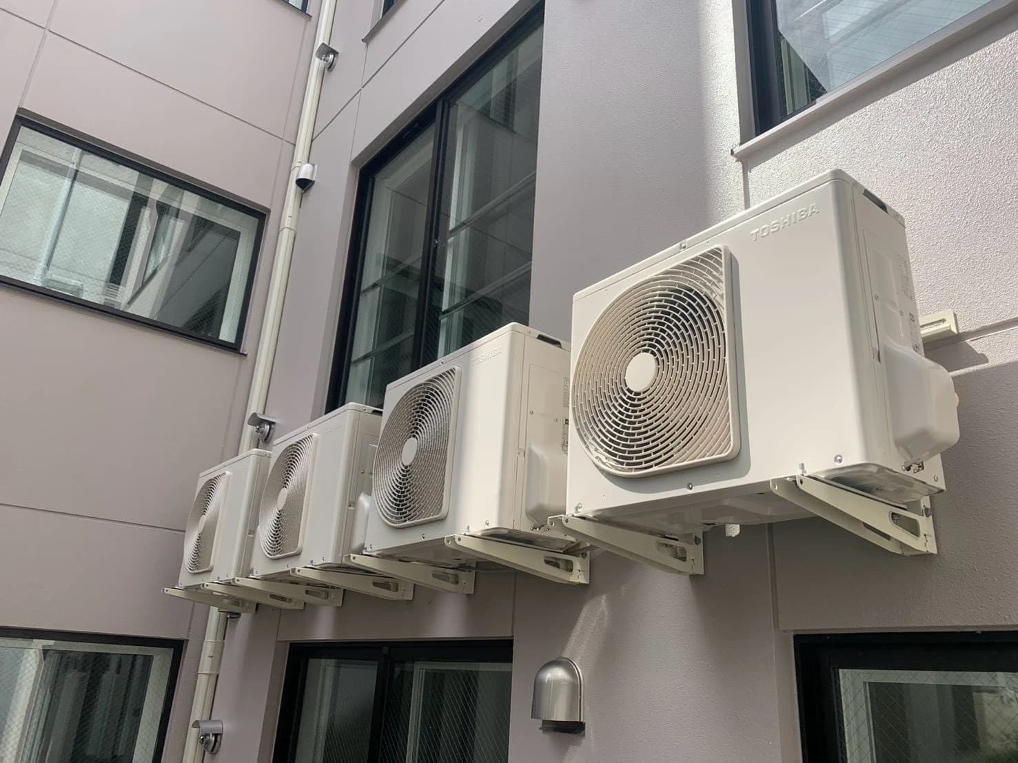 新築マンションの外壁に壁掛け金具で連装した東芝製エアコン室外機
